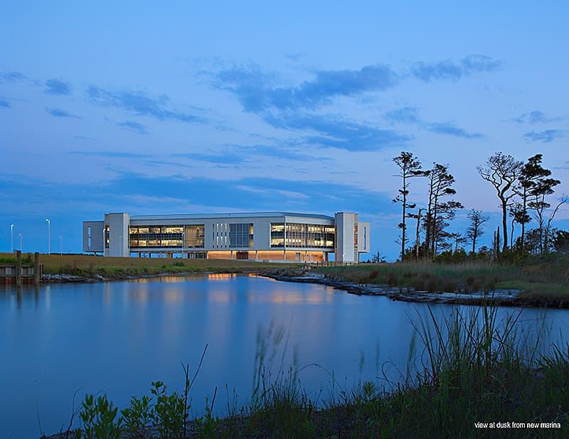 Photo of the Coastal Studies Institute building as viewed from a marina at dusk