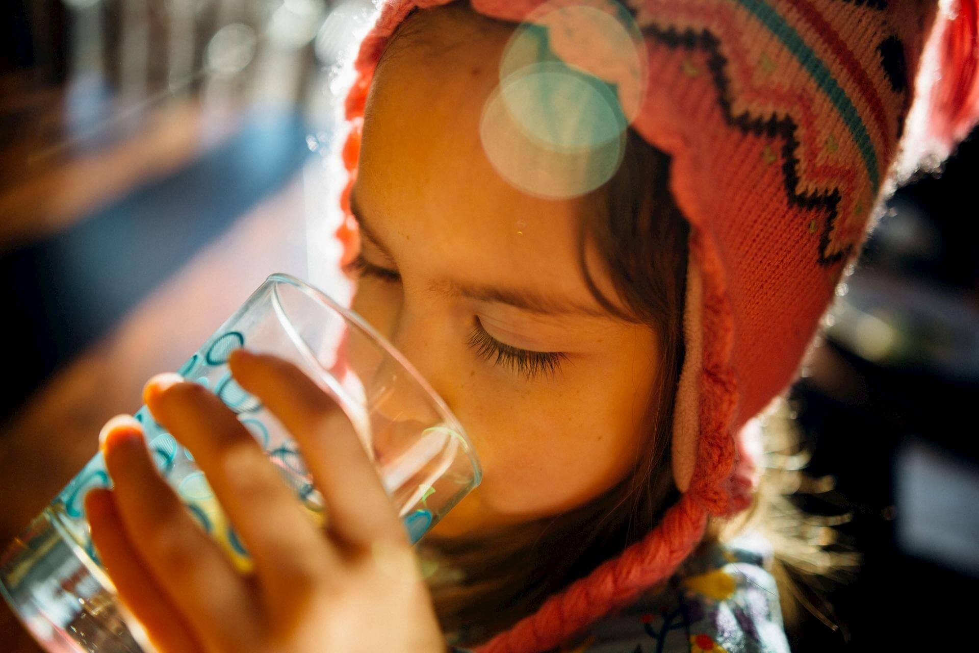 Photo of a young girl drinking a glass of water.